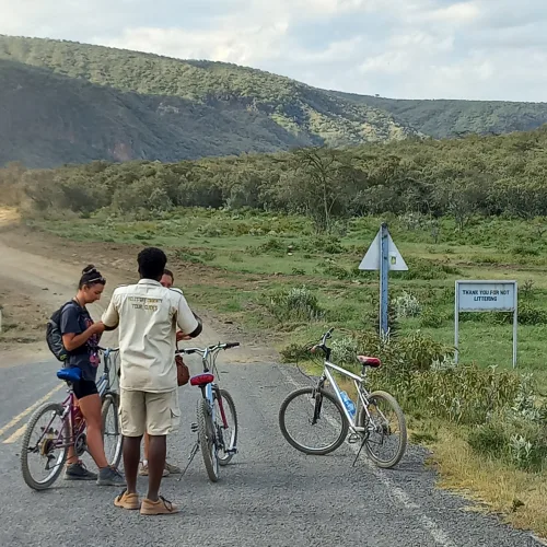 Tourists with bicycles and a local guide at Hell’s Gate National Park in Naivasha, Kenya, surrounded by scenic hills and open savannah