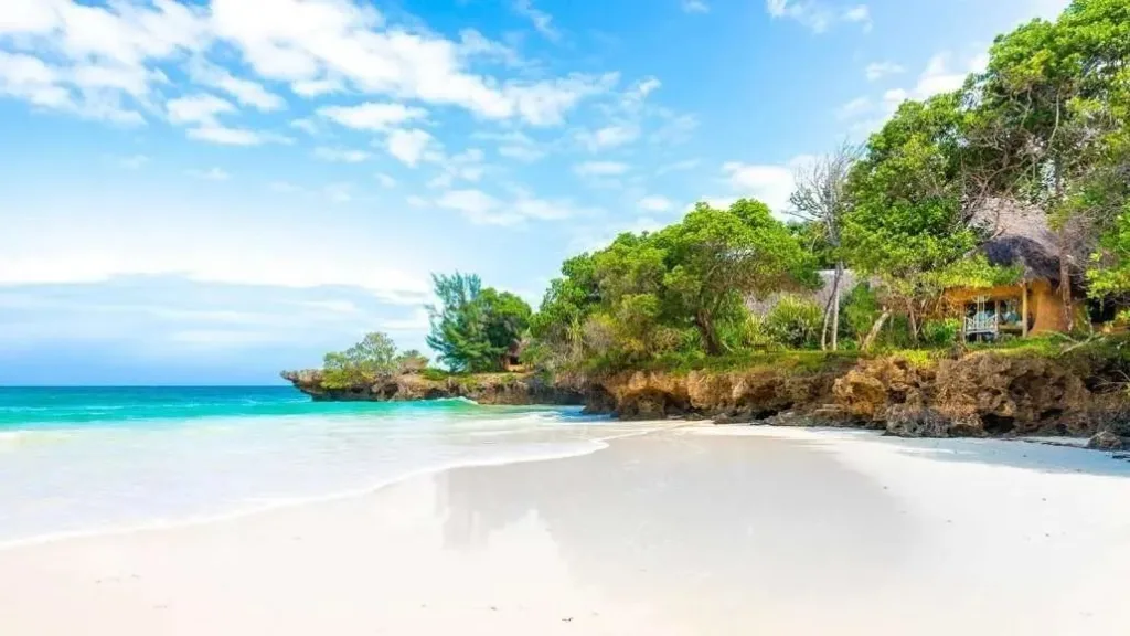 Diani beach scene with palm trees, thatch umbrellas, and people walking on the sand. Best Beach Spots in Diani.