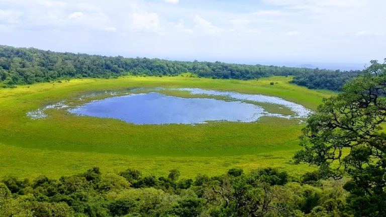 Marsabit's untamed wilderness: A stunning aerial view of a crater lake surrounded by lush green vegetation.